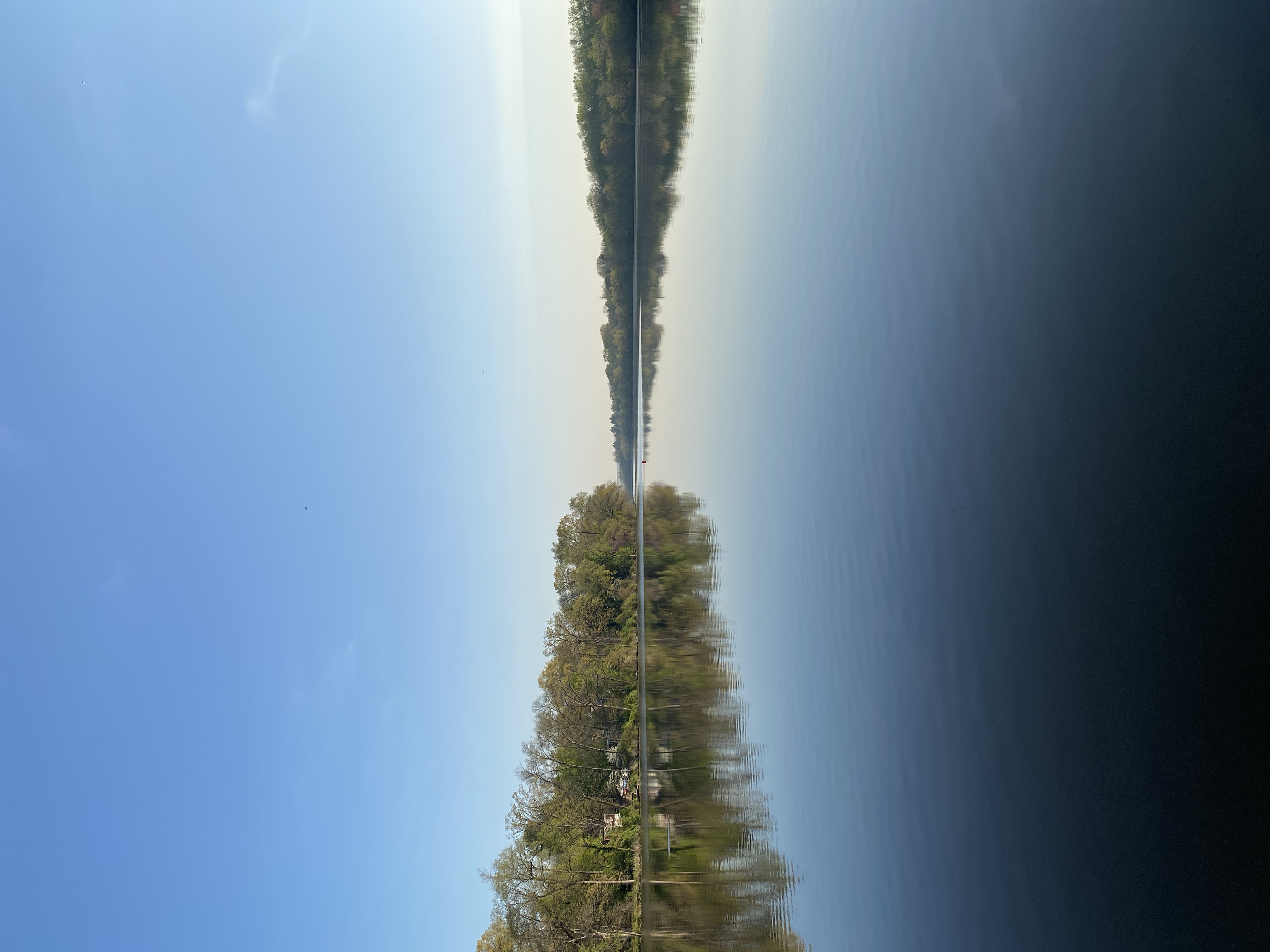 Flat, still water below a clear blue sky