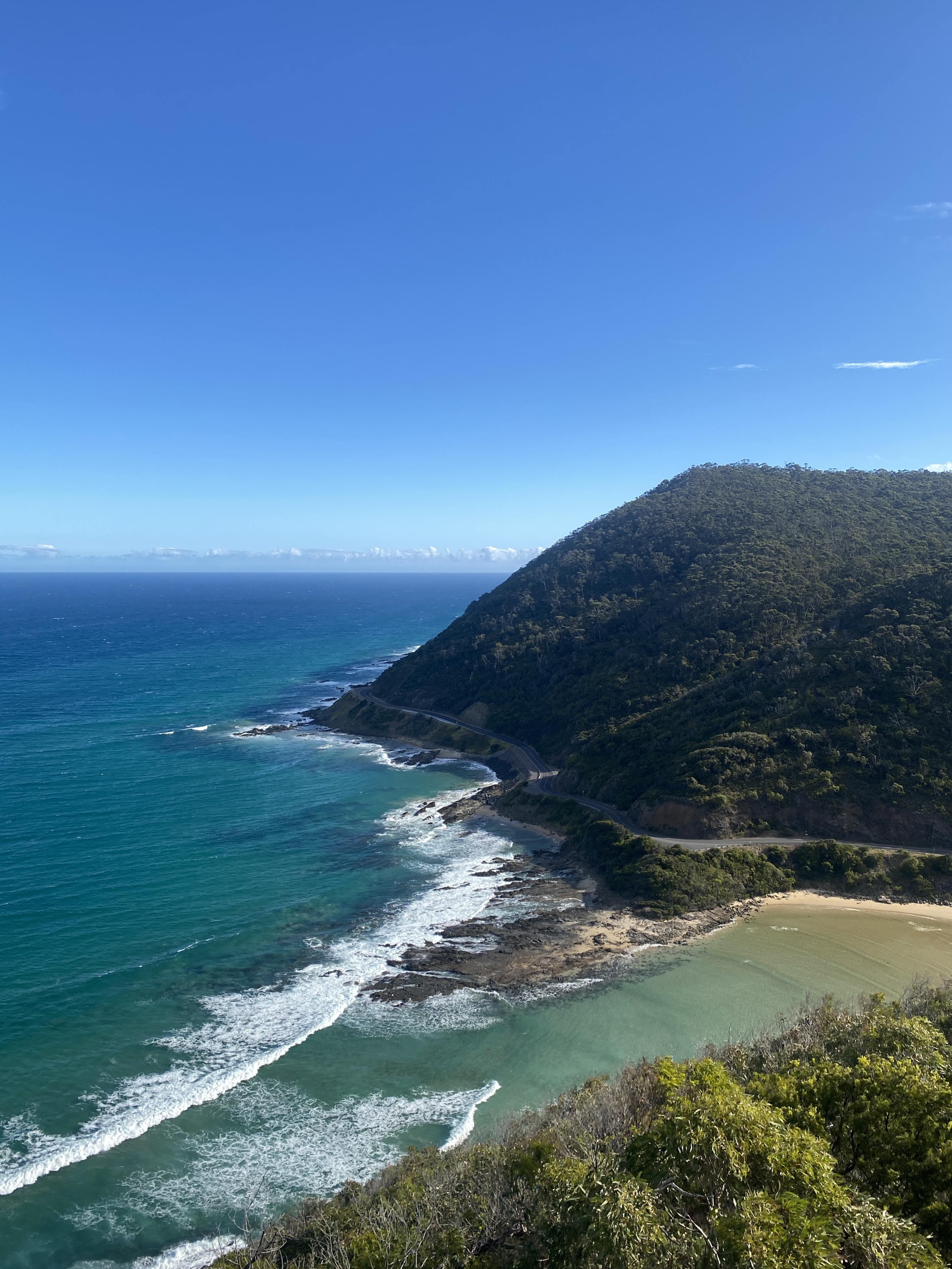 Waves breaking onto a winding coastal road