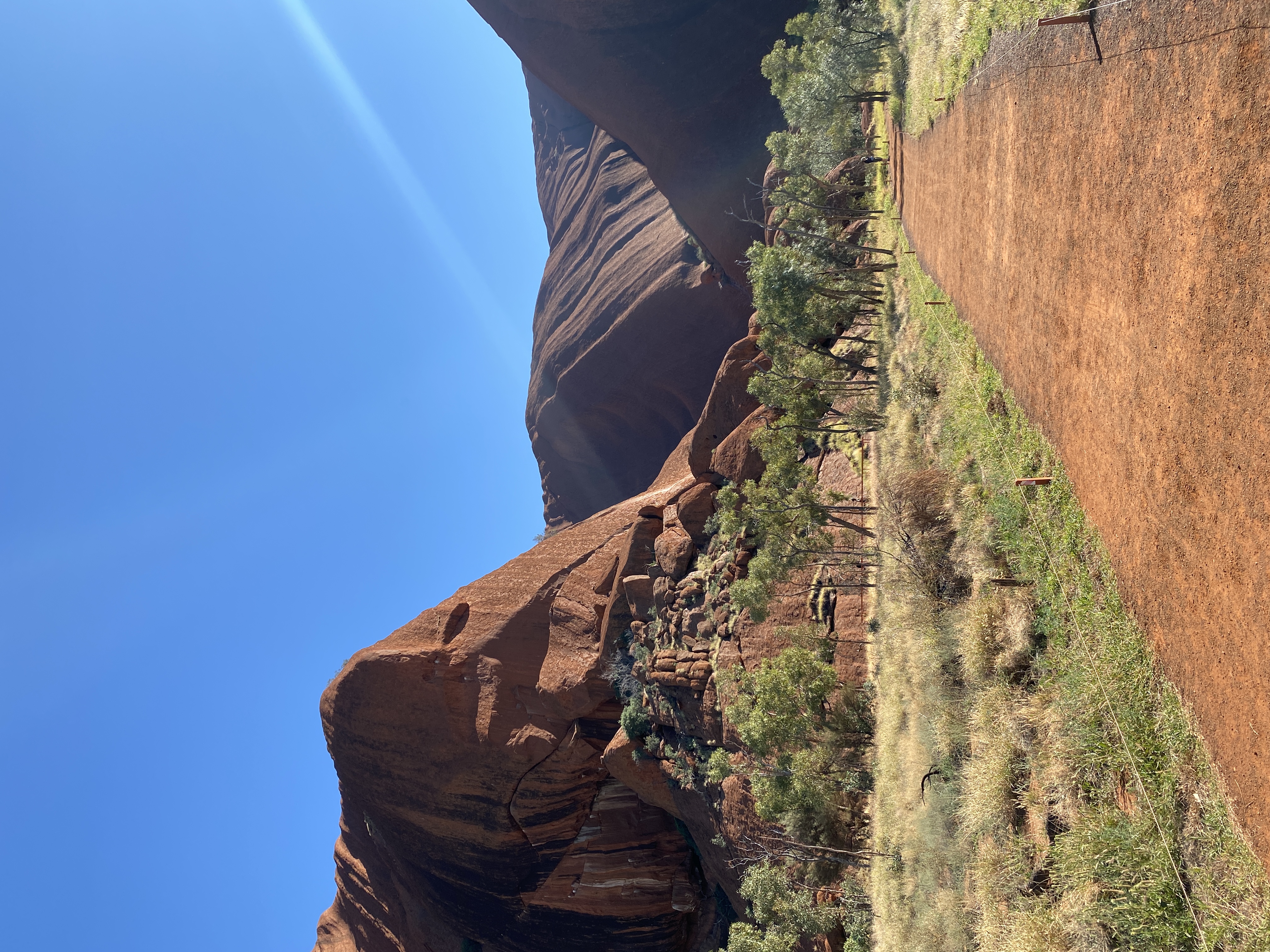 Section of Uluru with a red dirt path in the foreground