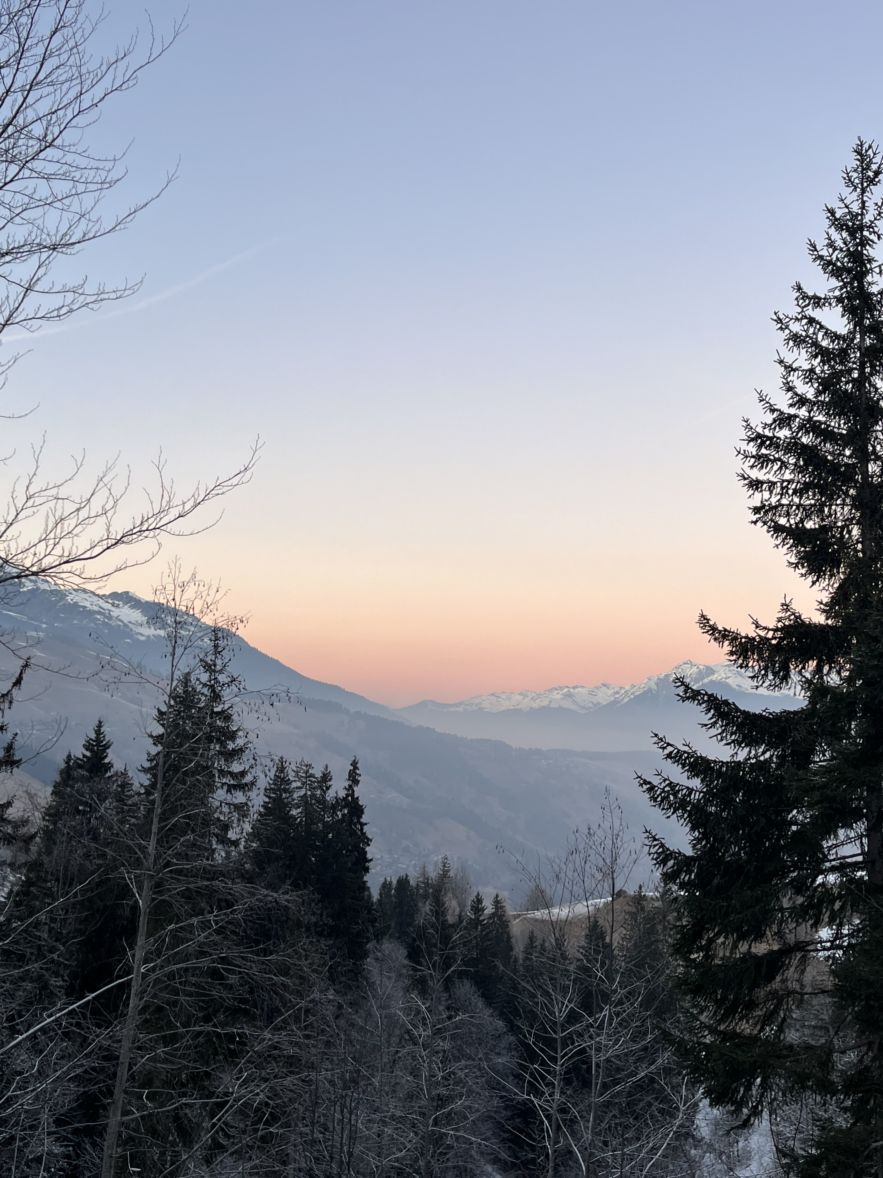 A sunset over snow-covered mountains and frosty trees